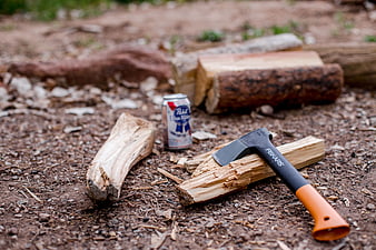 Fiskars axe and beer can on split firewood outdoors