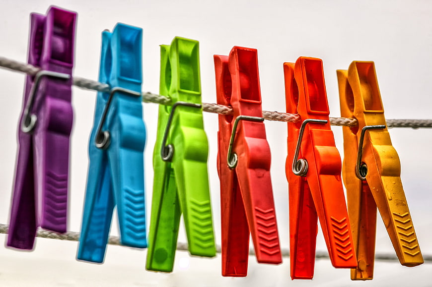 Colorful Plastic Clothespins Hanging On A Rope Against White Background