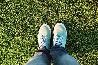 First-person view of turquoise sneakers on green grass