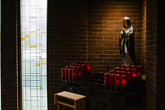 Statue of Virgin Mary with Candles in Church Niche