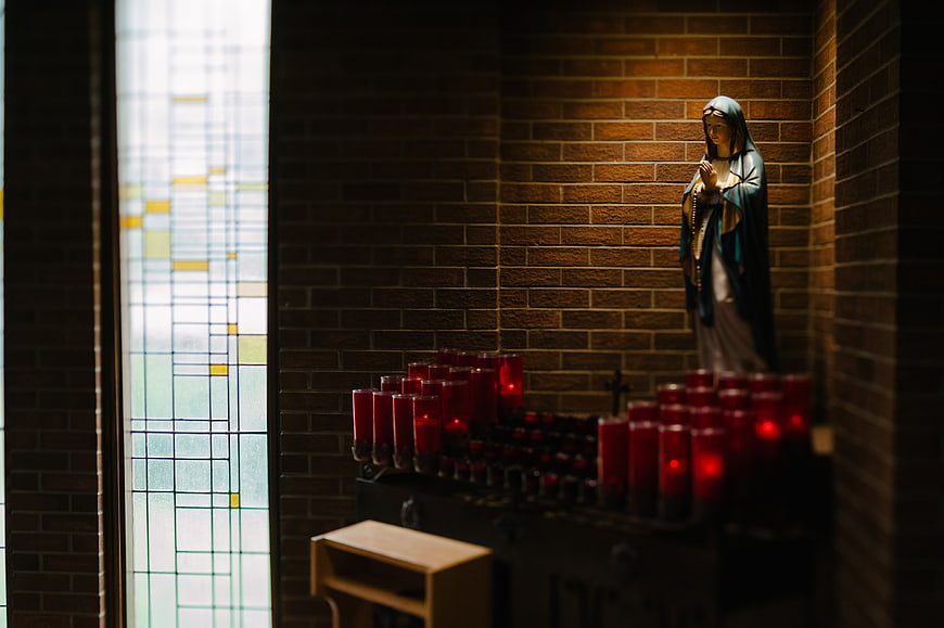 Statue of Virgin Mary with Candles in Church Niche