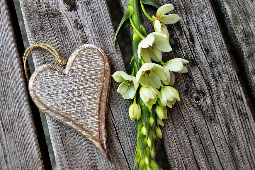 Rustic wooden heart and white flowers on weathered deck boards