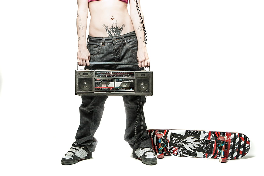 Woman with tattoos holding boombox and skateboard