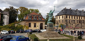 Panoramic view of bronze statue with cross in European town square