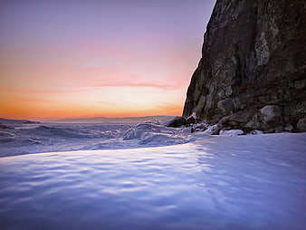 Serene Sunset Over Snowy Rocky Coastline