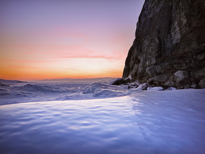 Serene Sunset Over Snowy Rocky Coastline