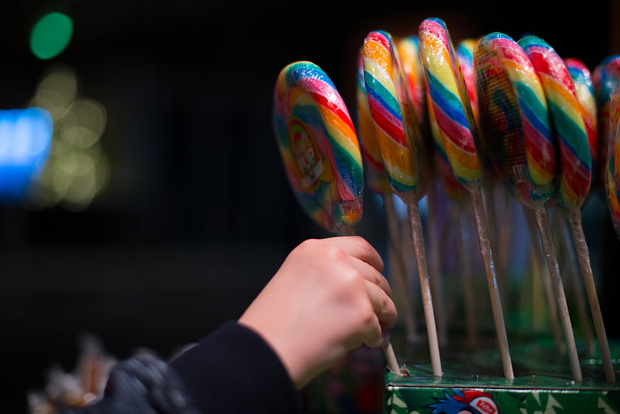 Child's Hand Reaching for Colorful Swirl Lollipops