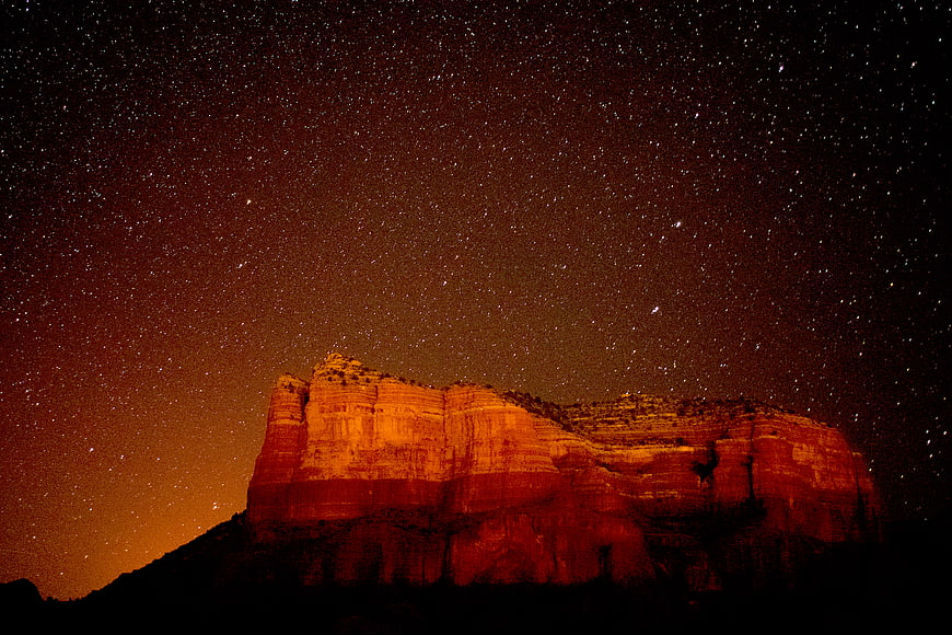 Red Rock Butte Illuminated Under Starry Night Sky