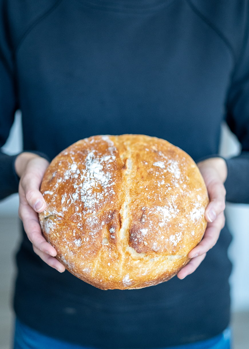 Hands holding fresh round loaf of artisan bread