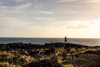 Silhouette of fisherman on rocky coast at sunrise