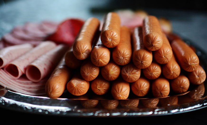 Close-up of stacked sausages and rolled ham on a silver platter