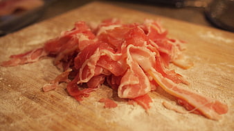 Raw sliced bacon strips on a wooden cutting board