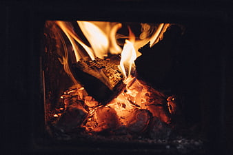 Close-up of burning logs and glowing embers in a wood stove
