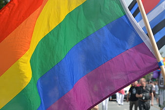 Close-up of a vibrant rainbow pride flag waving at a street parade