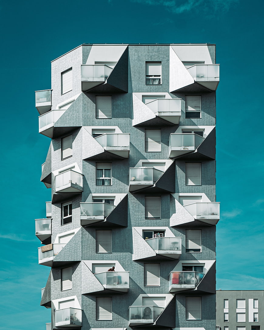 Modern geometric apartment building with teal sky background
