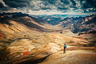 Man standing on a mountain ridge overlooking a vast arid valley