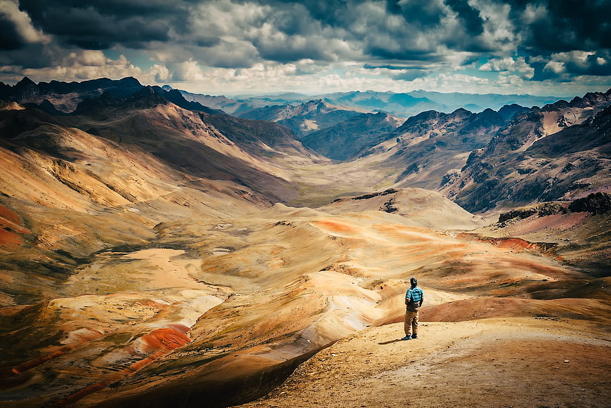 Man standing on a mountain ridge overlooking a vast arid valley