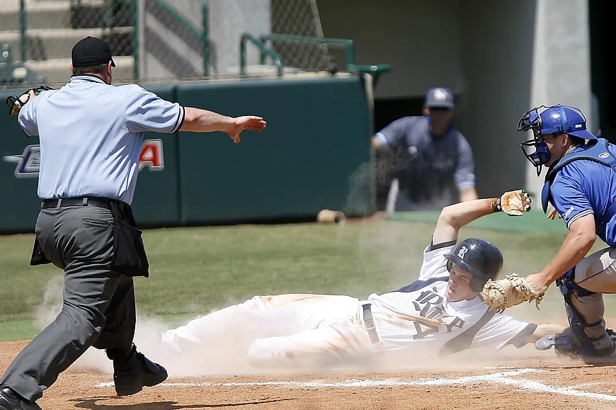 Baseball player sliding into home plate with umpire signaling safe