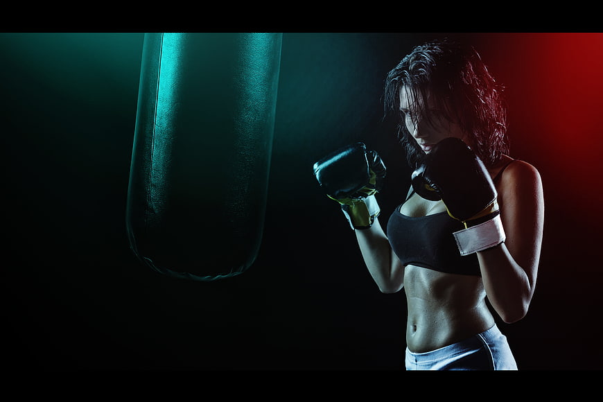 Female boxer training with punching bag in gym