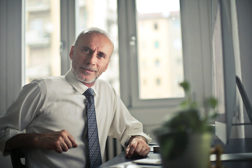 Senior Businessman Smiling at Office Desk