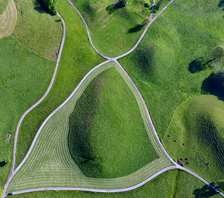 Aerial view of winding roads through lush green rolling hills