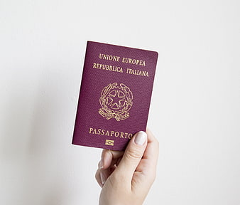 Hand holding Italian passport against white background