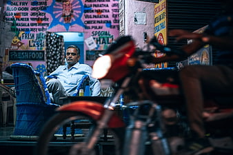Indian shop owner sitting outside restaurant at night