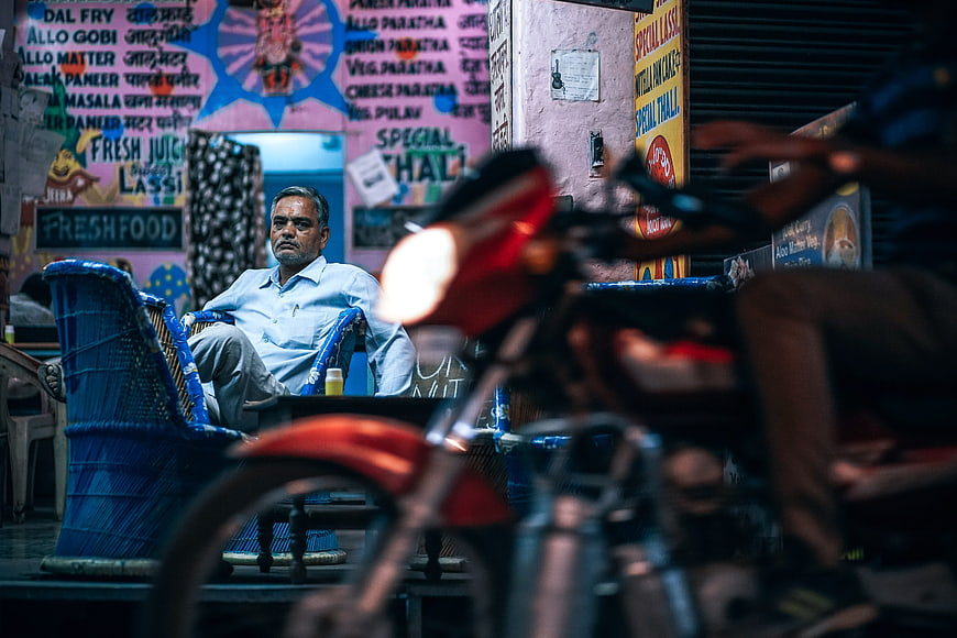 Indian shop owner sitting outside restaurant at night