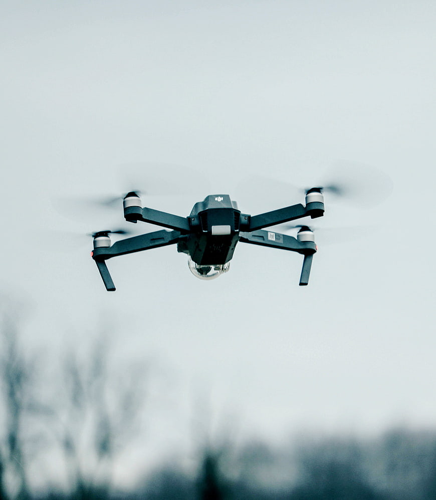 Black DJI drone flying against overcast sky