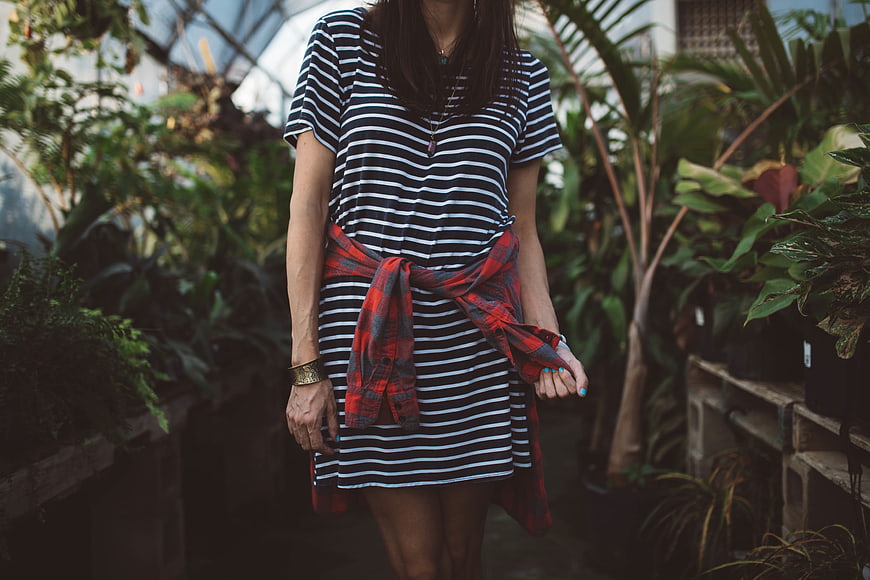 Woman in Striped Dress with Plaid Shirt in Greenhouse