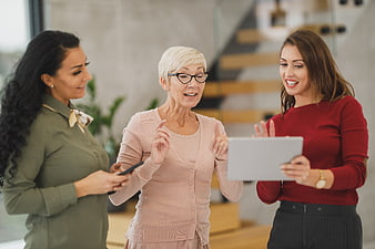 Three women collaborating with tablet in modern office