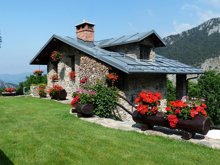 Stone cottage with red flowers in mountain landscape