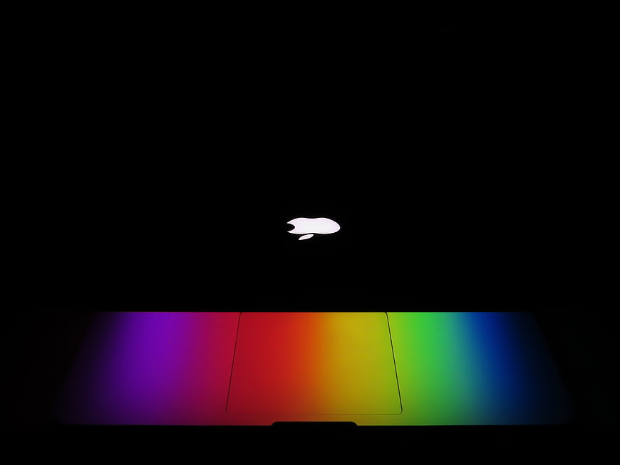 Glowing Apple Logo on Dark Background with Rainbow Light