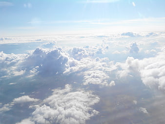 Aerial View of Fluffy White Clouds and Blue Sky from Airplane