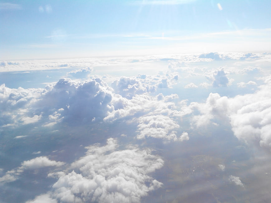 Aerial View of Fluffy White Clouds and Blue Sky from Airplane