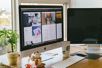 Web design workspace with Mac computer and lucky cat figurine