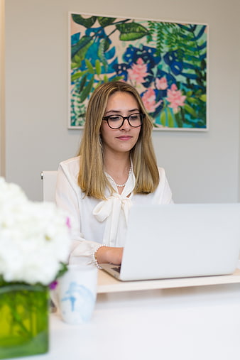 Professional woman with glasses working on laptop in bright office