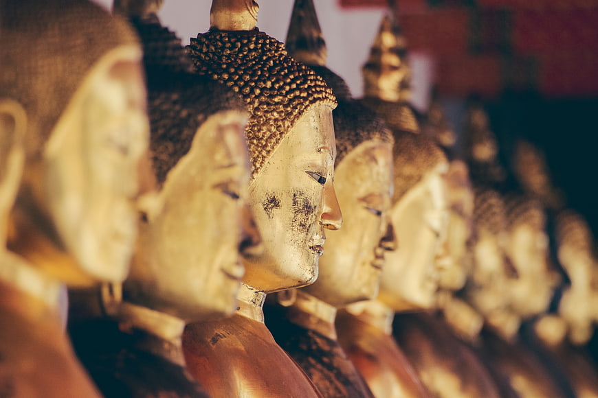Row of golden Buddha statues in profile view