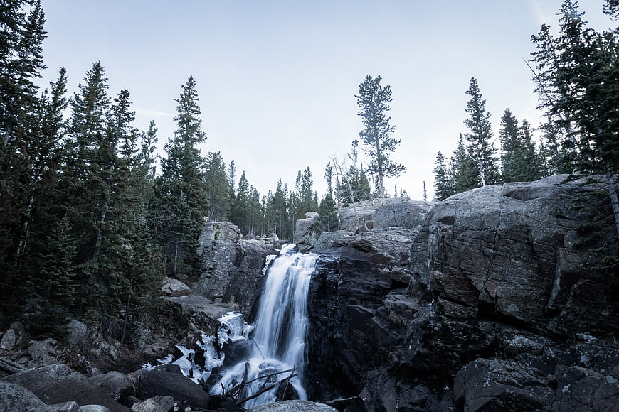 Serene Waterfall Cascading Over Rocks in Pine Forest