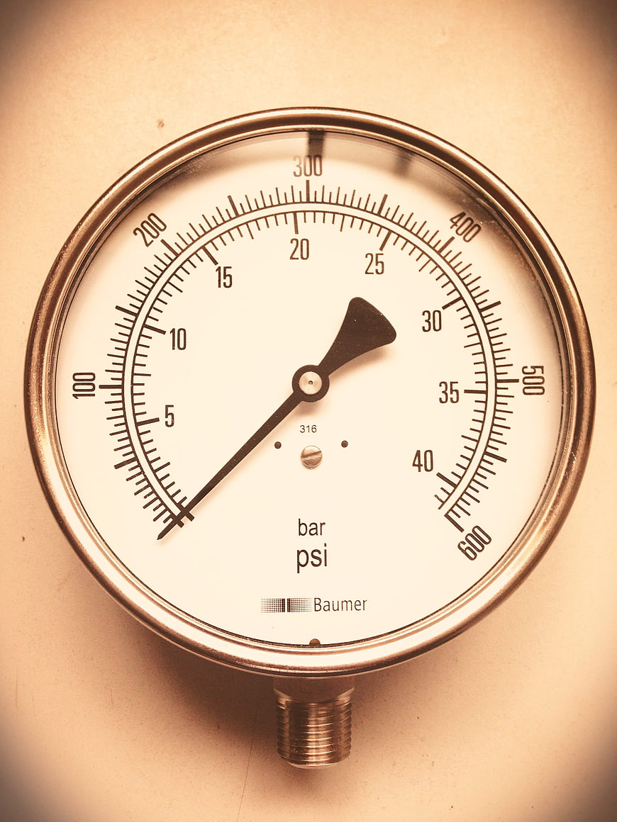 Close-up of a vintage industrial pressure gauge with bar and psi scale