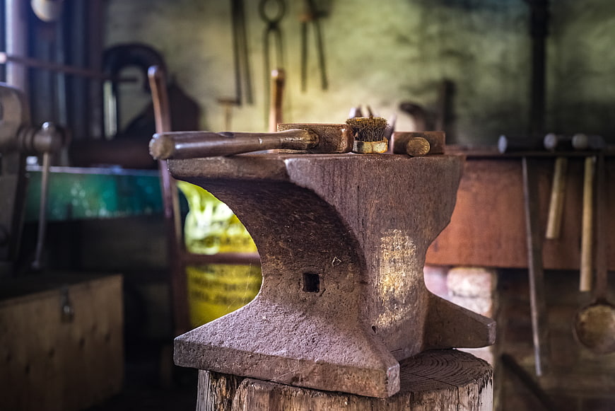 Rusty anvil with hammer in old blacksmith workshop