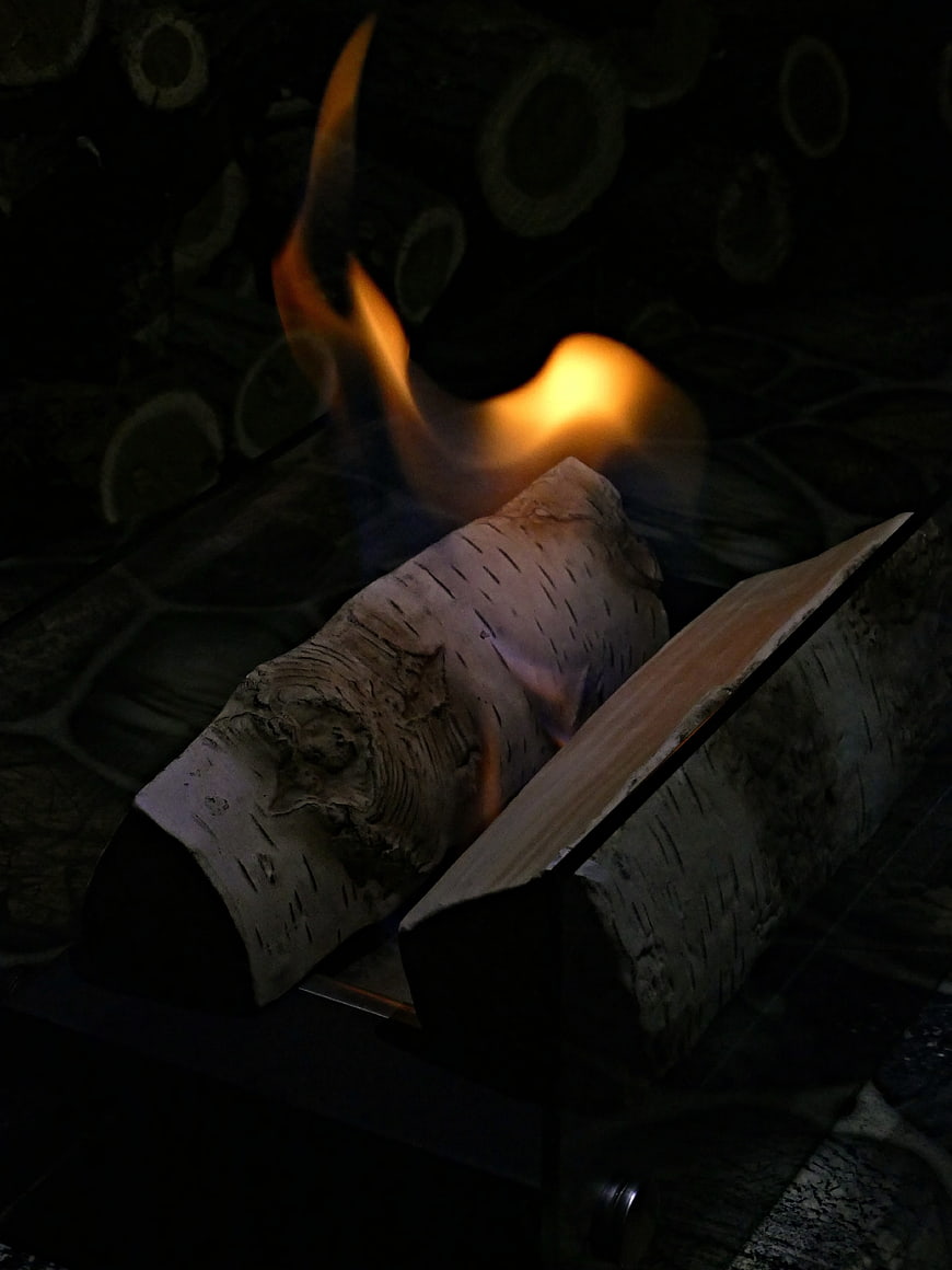 Burning birch logs in a dark stone fireplace