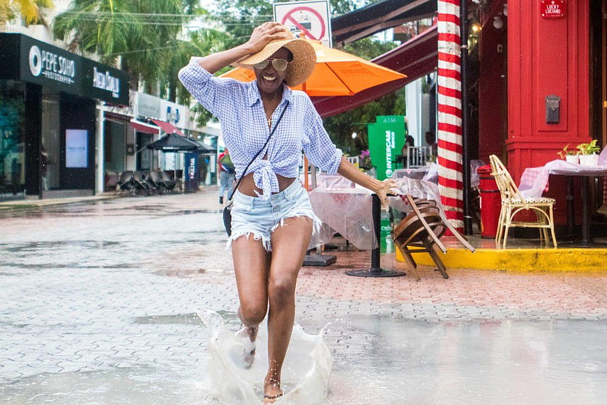 Happy Woman Running Through Puddle on Rainy Street