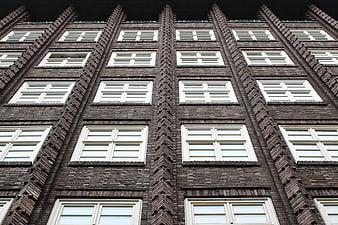 Low angle view of dark brick building facade with white windows