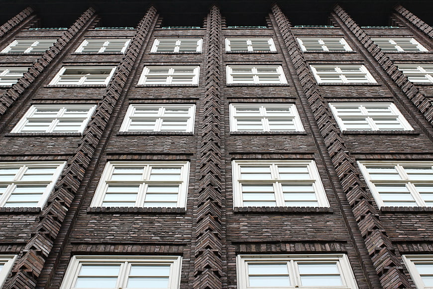 Low angle view of dark brick building facade with white windows