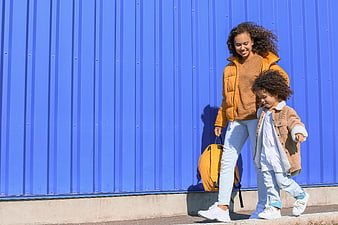 Mother and daughter walking past blue wall