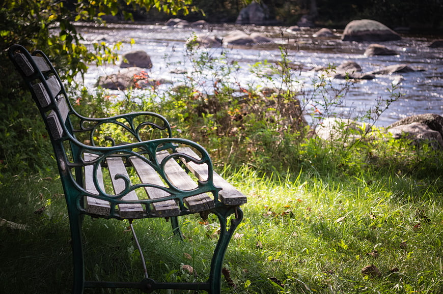Vintage green park bench by a flowing river