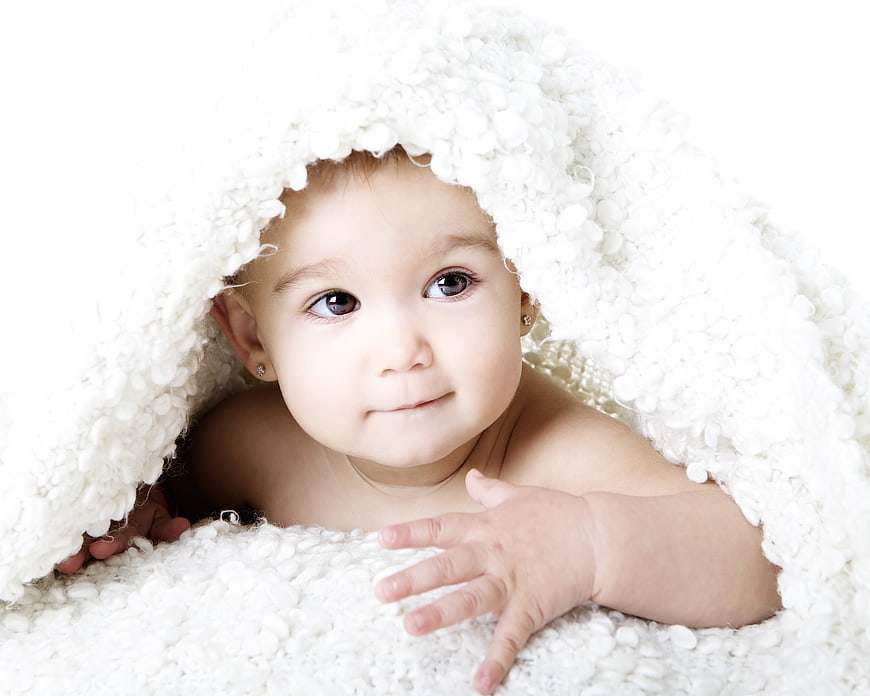Cute Baby Girl Peeking Out From White Fluffy Blanket