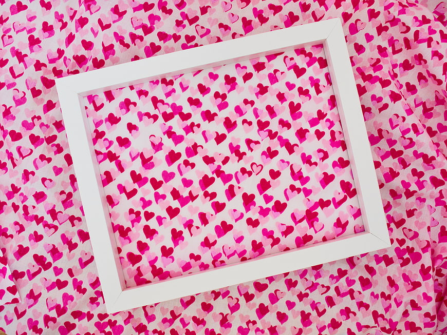 White Frame on Pink Heart Patterned Fabric Background