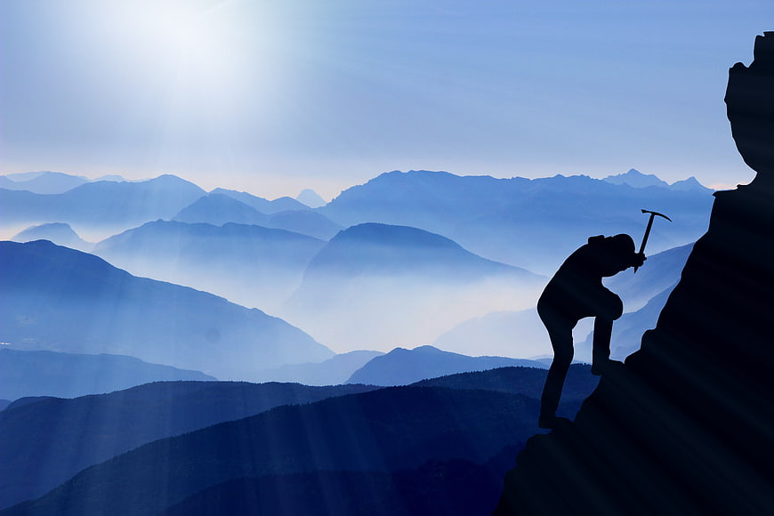 Silhouette of Mountaineer Climbing Mountain Peak at Sunrise